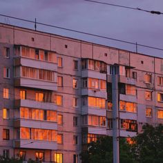 an apartment building with many windows lit up in the evening time, and trees outside