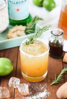 a close up of a drink in a glass with rosemary garnish