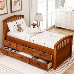 a wooden bed with drawers underneath it in a room next to a lamp and pictures on the wall