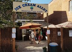 people are standing under an ice cream alley sign