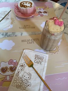 two hello kitty cafe menus on a table next to a cup of coffee and a fork