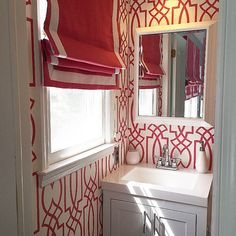 a bathroom with red and white wallpaper on the walls, sink and vanity area