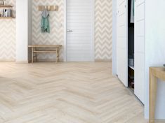 an empty room with chevron wood flooring and shelving unit in the background