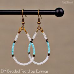 two pairs of beaded teardrop earrings hanging from a hook on a black pole