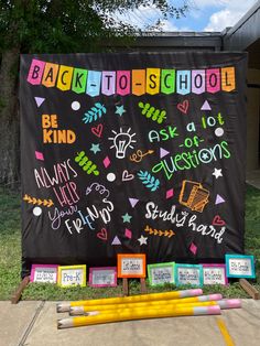 back to school sign with pencils and markers on the ground in front of it