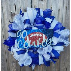 a blue and white football wreath with the word daddy on it, hanging from a wooden fence