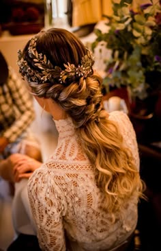 a woman with long hair wearing a flower crown in her hair, sitting on a chair