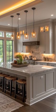 a large kitchen with an island in the middle and lights hanging from it's ceiling