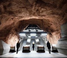 two people are standing at the bottom of an escalator in a large building