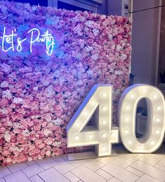 the number forty is displayed in front of a flower wall with pink and white flowers