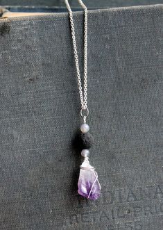 This short necklace has a bead and amethyst pendant hanging from a silver chain. The black bead is a lava rock which can be used to diffuse a drop of essential oil. Black Amethyst Gemstone Beads Necklace, Silver Amethyst Necklace For Meditation, Lava Stone Necklace With Natural Stones For Gift, Pendant Necklace Outfit, Vintage Pendant Necklace, Pendant Necklace Simple, Crystal Necklaces, Lava Rock, Amethyst Pendant