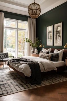 a bedroom with dark green walls and white bedding, wooden flooring, large windows