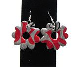 pair of red and silver earrings sitting on top of a black stand next to each other