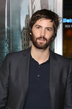 a man with a beard standing in front of a poster