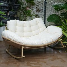 a white chair sitting on top of a hard wood floor next to potted plants