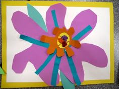 a flower made out of paper sitting on top of a piece of cardboard with scissors