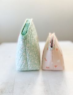 two small purses sitting on top of a white table next to eachother