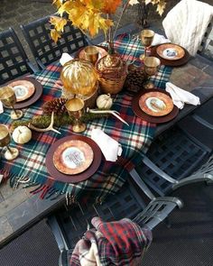 an outdoor table set with plates and place settings