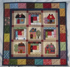 a quilted wall hanging with houses on it