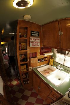 the inside of a camper with a sink, mirror and cupboards on it