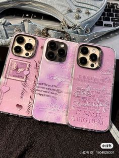 two pink iphone cases sitting on top of a table next to a bag and purse