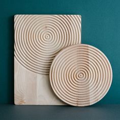 two wooden coasters sitting on top of a table next to each other with spiral designs