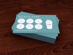 three blue business cards sitting on top of a wooden table next to a coffee cup