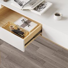 an open drawer on a desk with books and eyeglasses