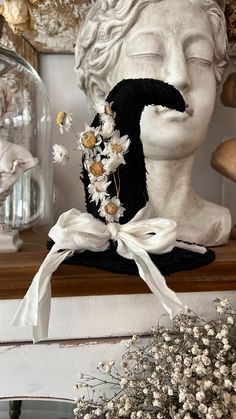 a white busturine with flowers on it next to a glass vase and mirror