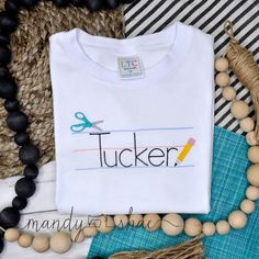 Your child's printed name and handwriting paper will be stitched onto a white t-shirt. If you would like to request a size larger than listed, please message me and I will be happy to check availability. All designs are stitched onto 100% cotton, boutique quality fabric. A soft mesh is ironed onto the back of the stitching to prevent irritation of your child's skin. Please refer to the size chart in photos before ordering. 💦Machine wash inside out in cold water, and lay flat to dry. If needed, White Shirt With Funny Text For School, White Funny Text Shirt For School, White T-shirt With Machine Embroidery For Gift, White T-shirt With Machine Embroidery As Gift, Customizable Cotton School Shirt, Cotton Shirt With Name Print For School Events, Cotton T-shirt With Embroidered Text For School, Cotton T-shirt With Embroidered Text, School Cotton Tops With Custom Text