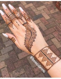 a woman's hand with henna tattoos on it and white nail polishes