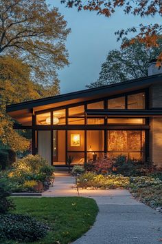 a modern house in the evening with its lights on and landscaping around it's perimeter