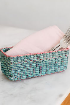 a fork and napkin holder on a marble counter top with a pink cloth in it