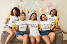 the bridesmaids are sitting on the couch with their drinks in hand and smiling