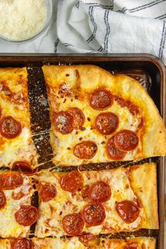 pepperoni pizza cut into eight slices on a baking pan with cheese and seasoning