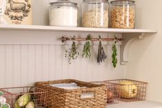 some baskets are sitting on the shelf in front of two jars and an open door