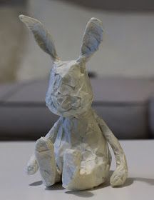 a paper mache rabbit sitting on top of a white table next to a couch