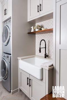 a kitchen with white cabinets and gray appliances, including a washer and dryer