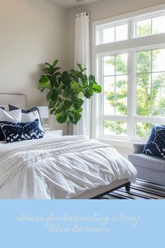 a bed with white sheets and blue pillows in front of a window that has a potted plant on it