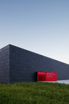 a large black building sitting on top of a lush green field next to a red fire hydrant