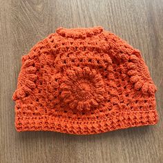 an orange crocheted hat sitting on top of a wooden table