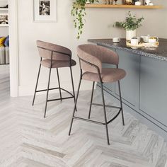 two bar stools sitting next to each other in front of a kitchen counter top