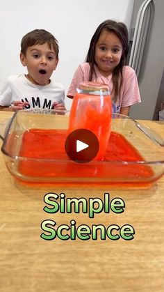 two young children sitting at a table with an orange substance in a glass bowl on top of it