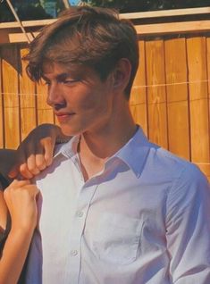 a young man and woman standing next to each other in front of a wooden fence