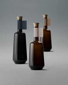 three bottles with labels on them sitting next to each other in front of a gray background