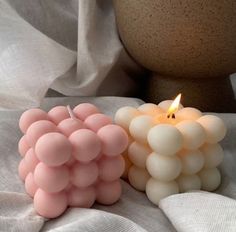 two candles sitting next to each other on top of a white cloth covered tablecloth