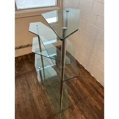 a glass table with metal legs in front of a brick wall and hardwood flooring