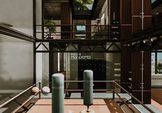 two candles sitting on top of a wooden table in front of a glass building with windows