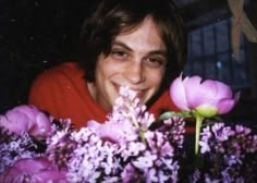 a woman is smiling and holding flowers in front of her