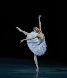 the ballerina is dressed in white and has her arms stretched out as she stands on one leg